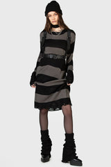 goth girl wearing a black and grunge gray striped dress with a high-waisted punk belted harness, black boots, and a black beanie on a white background.