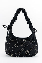 Black handbag with safety pin embellishments on a white background