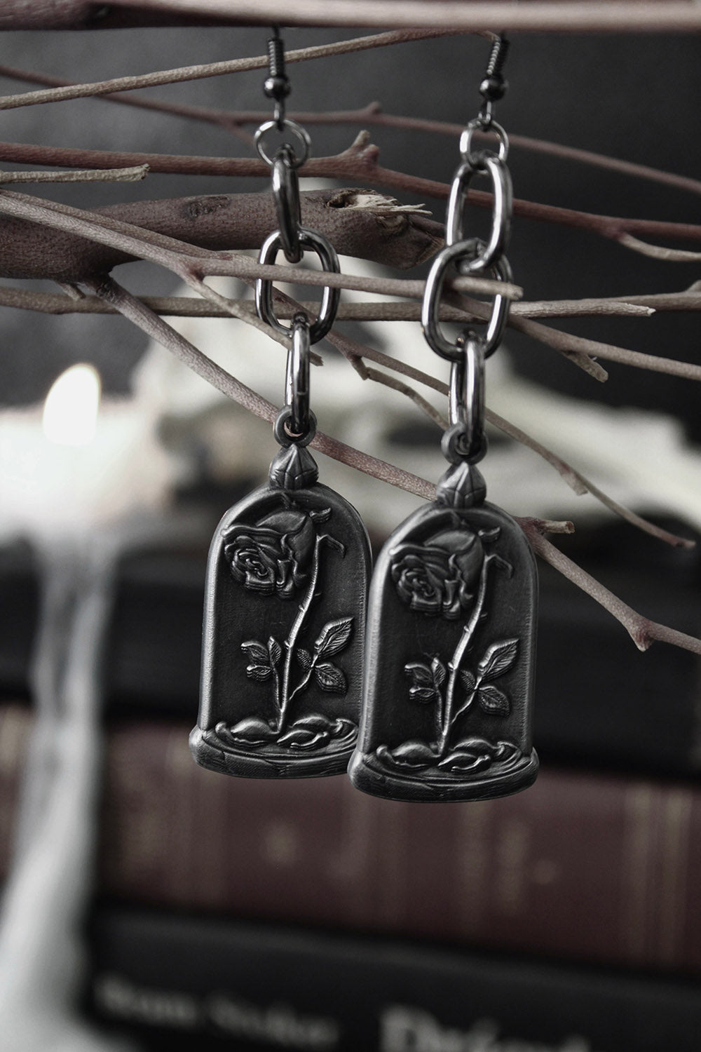 Pair of silver earrings with floral designs hanging from branches.