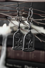 Pair of silver earrings with floral designs hanging from branches.