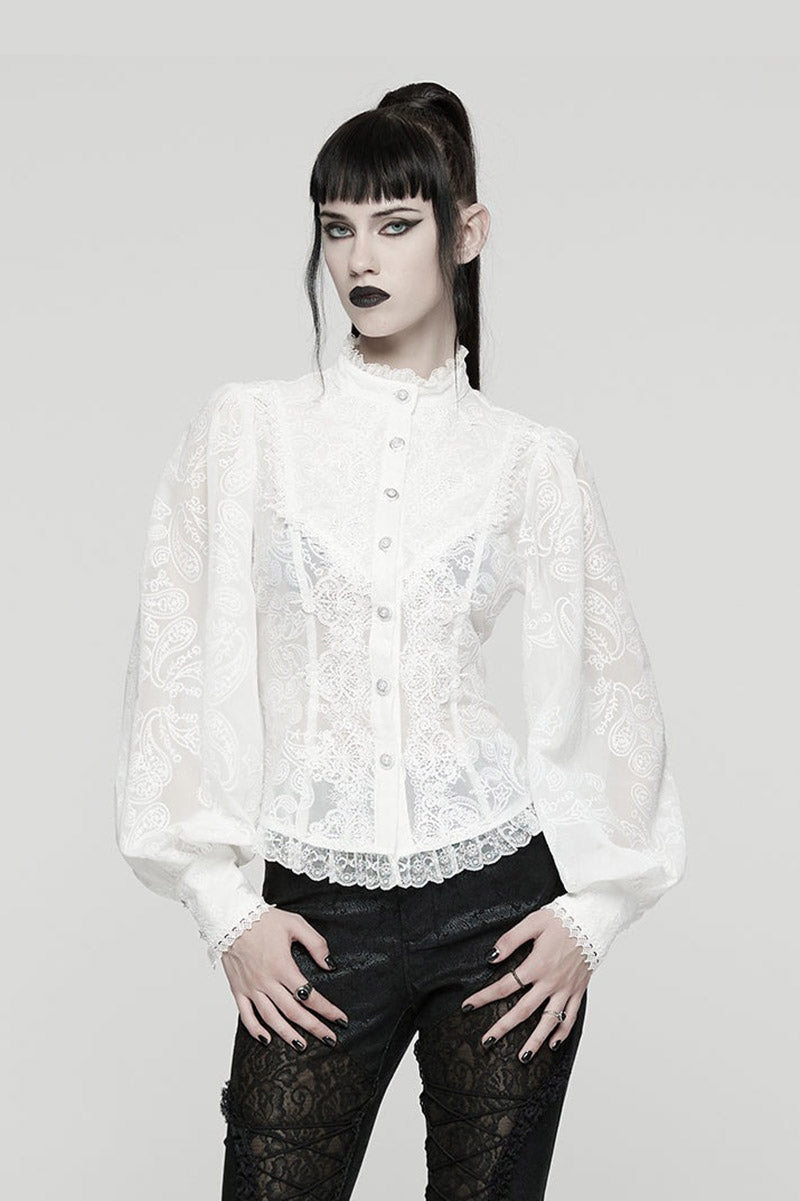 Person wearing a white lace blouse with black pants on a gray background