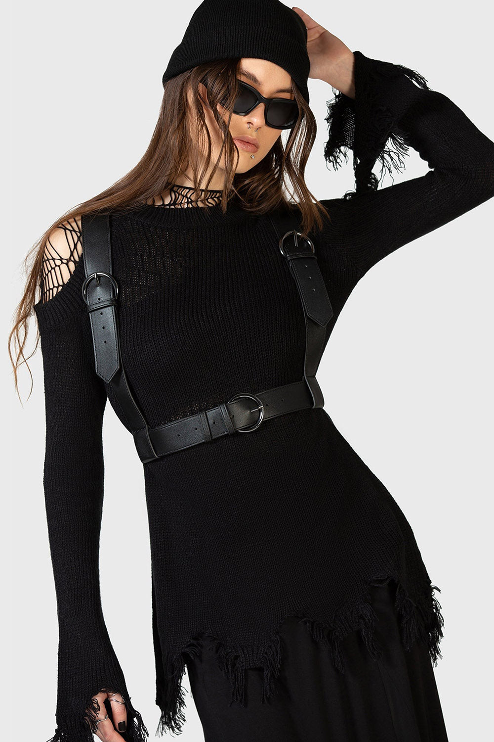 Woman wearing a black outfit with a gothic suspender harness on a white background
