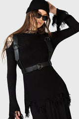 Woman wearing a black outfit with a gothic suspender harness on a white background
