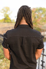 Dark gothic mens short sleeve shirt with buckle accents on the shoulders and chest pockets for punk fashion industrial aesthetics and alternative style