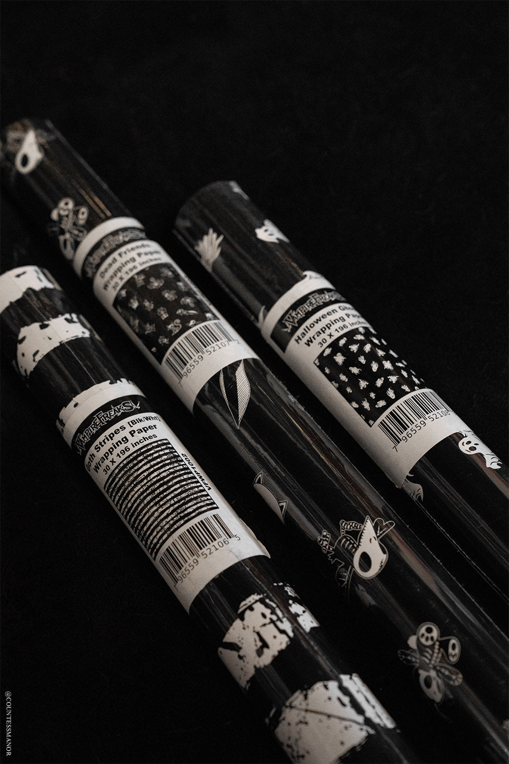 black and white striped wrapping paper and ghost wrapping paper and a roll of Skeleton animal gift wrap