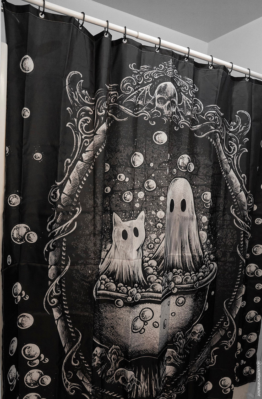 Decorative shower curtain with ghost and cat design on a black background
