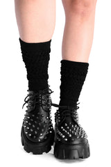 Black spiked platform shoes with black socks on a white background