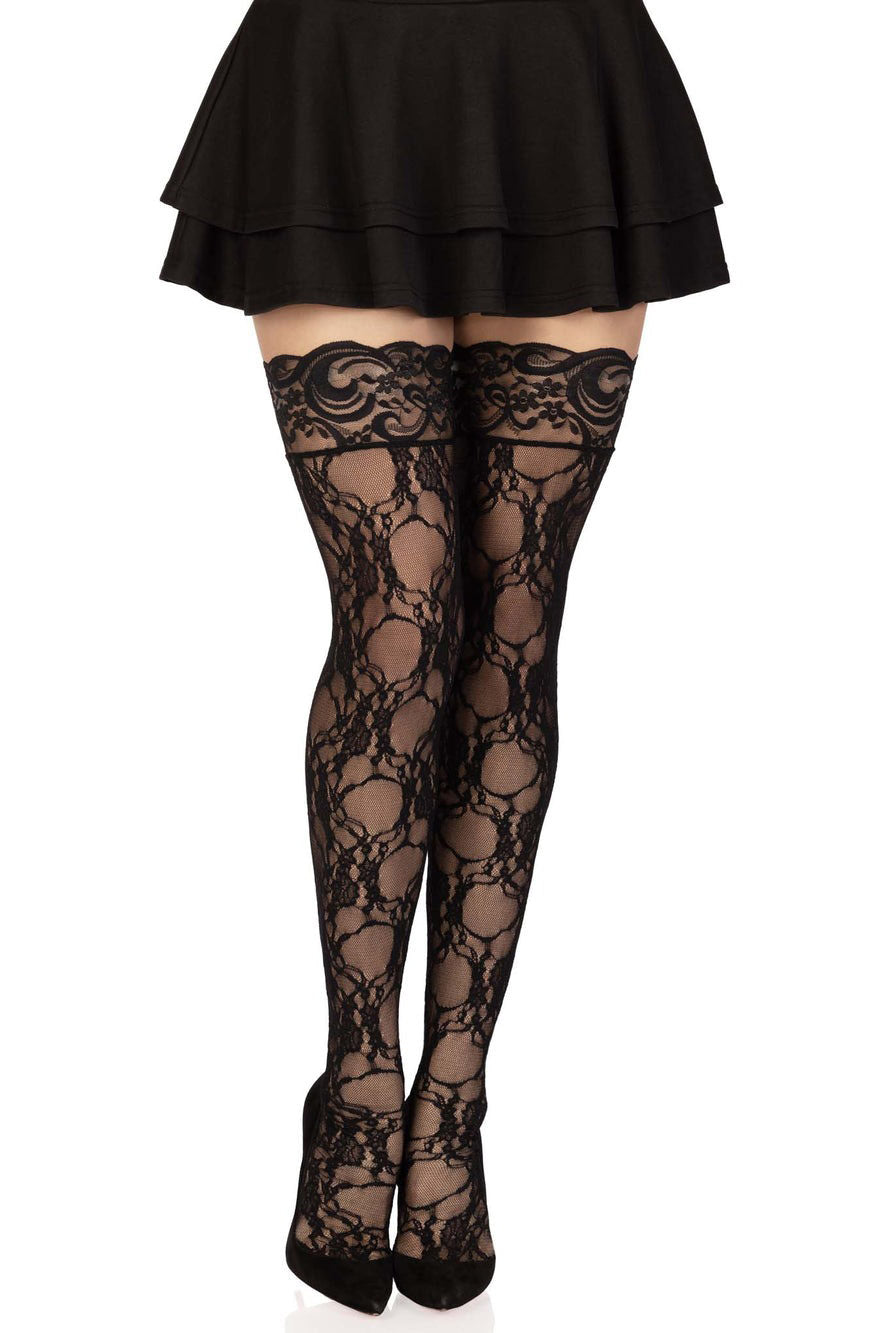 A pair of black floral lace thigh high stockings worn with a black skirt.