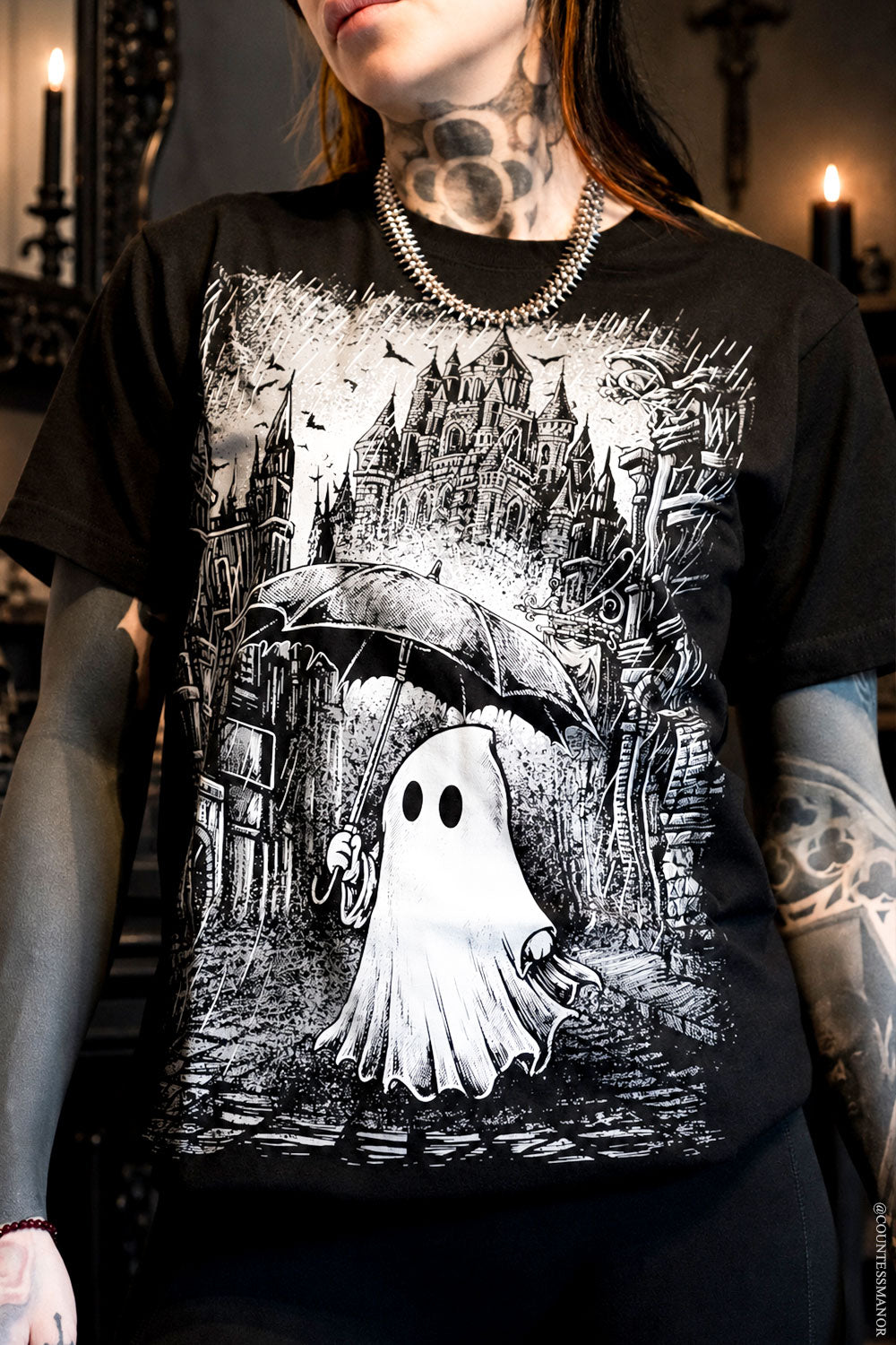 black tshirt with white printed artwork of ghost holding an umbrella walking in front of a castle in the rain