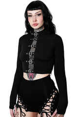 Woman wearing a black long-sleeve top with lace-up details and a matching skirt on a white background.