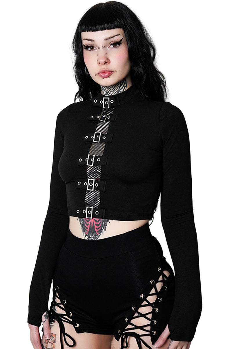 Woman wearing a black long-sleeve top with lace-up details and a matching skirt on a white background.
