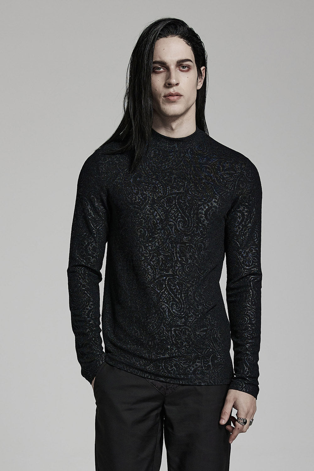 A person wearing a high-collared, slim fit black top with baroque patterns. The top appears to be made of a stretchy knit fabric.