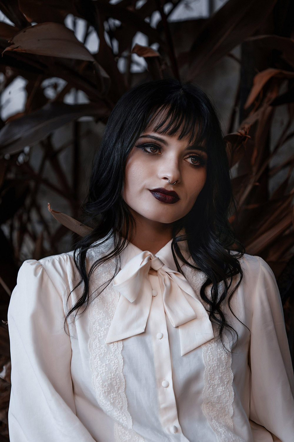 Woman wearing a witchy white blouse with a dark background