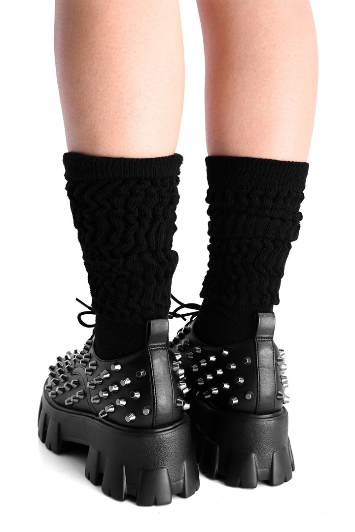 Black spiked platform boots with high black socks on a white background