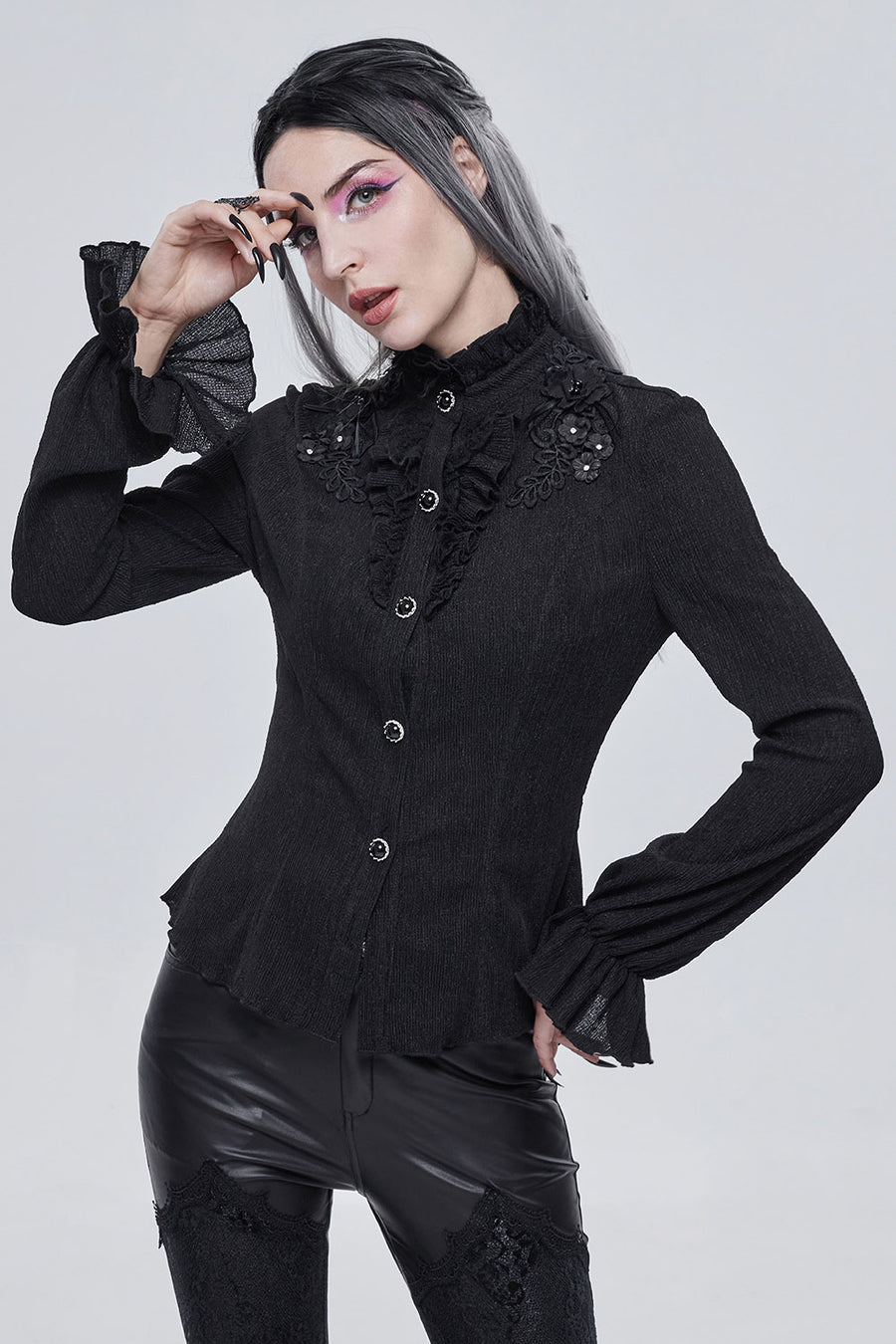 Person wearing a black gothic-style blouse with lace details on a white background
