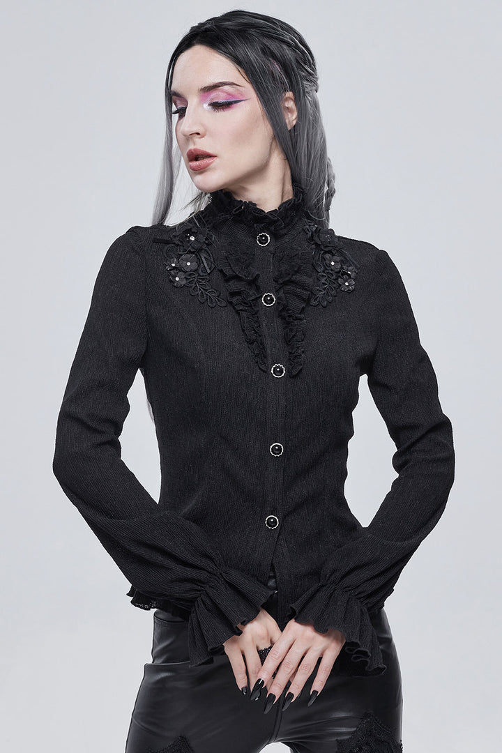 Woman wearing a black gothic-style blouse with ruffled details on a white background
