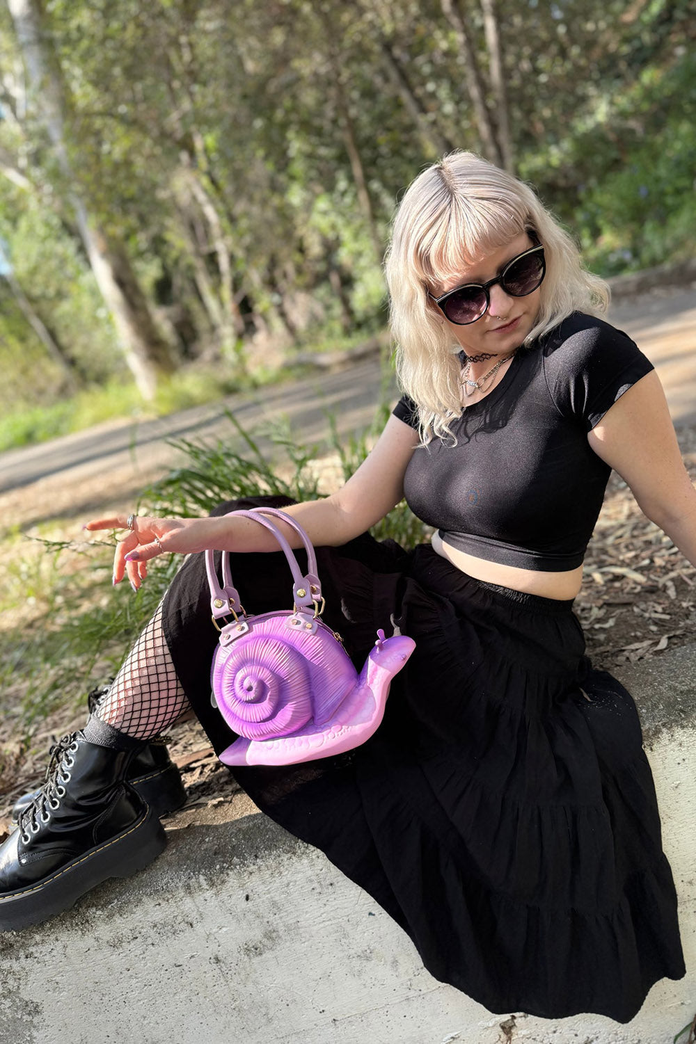 Person holding a purple snail-shaped handbag outdoors