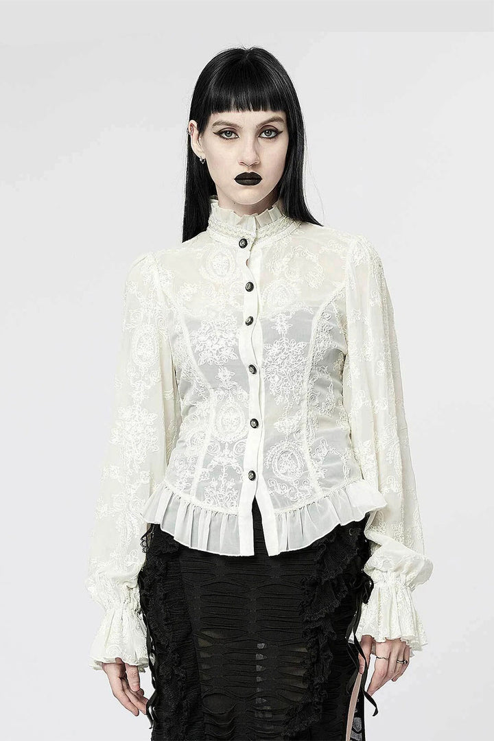Person wearing a white lace blouse with black buttons on a white background