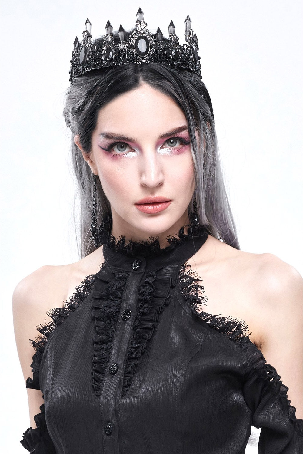 Woman wearing a black dress with lace details and a decorative headpiece on a white background