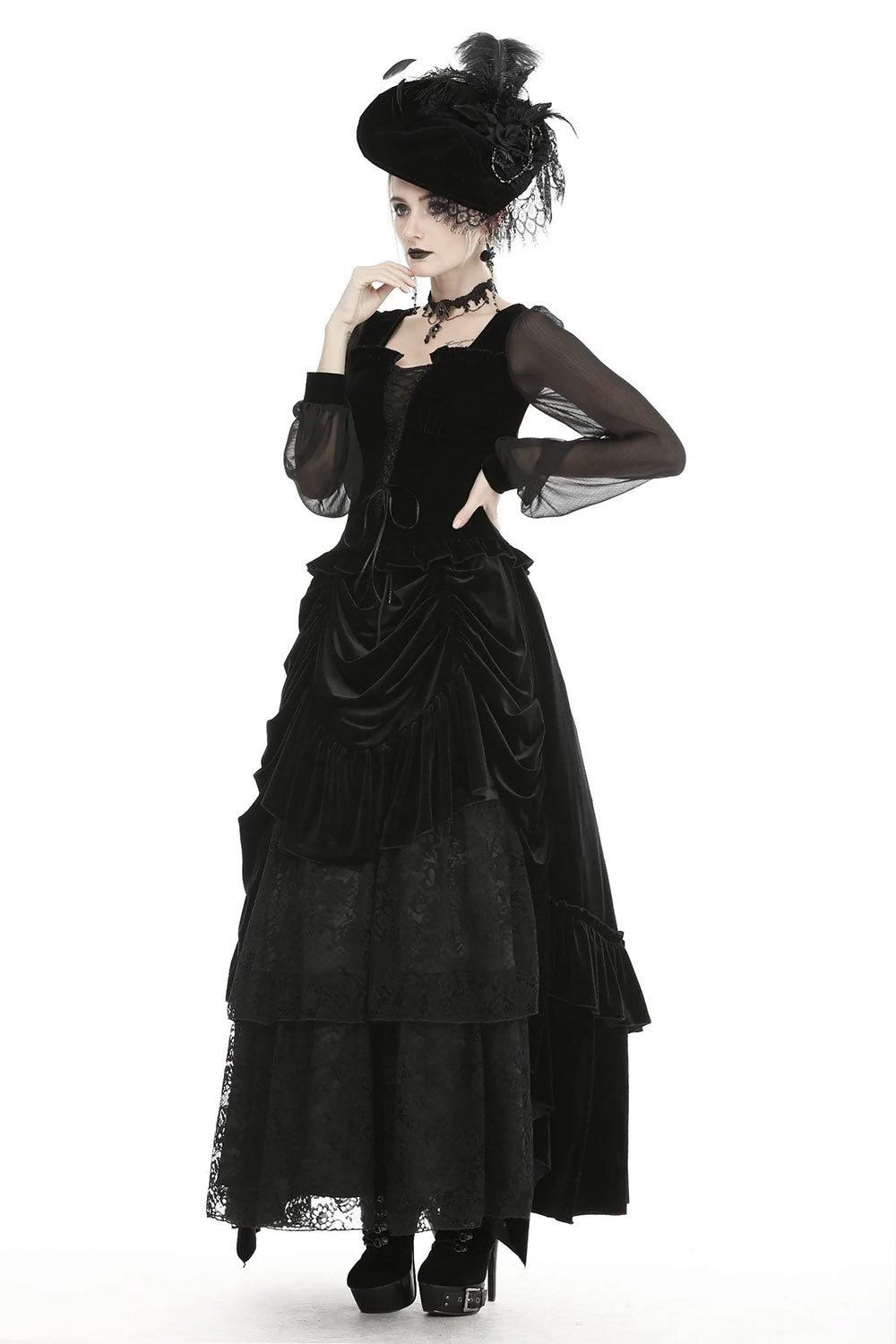 A woman wearing a high-waisted, tiered ruffles, floral lace, and soft velvet black maxi skirt with an elastic waistband and front tie closure.