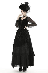 A woman wearing a high-waisted, tiered ruffles, floral lace, and soft velvet black maxi skirt with an elastic waistband and front tie closure.